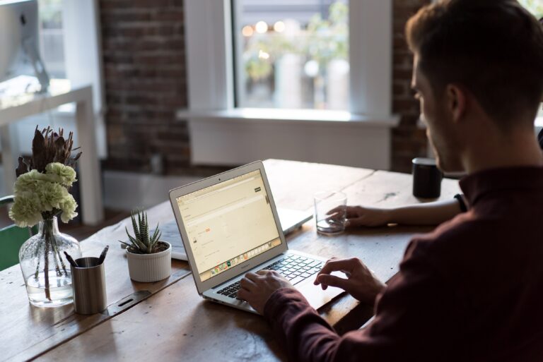 Man typing on computer downloading bank statements at table